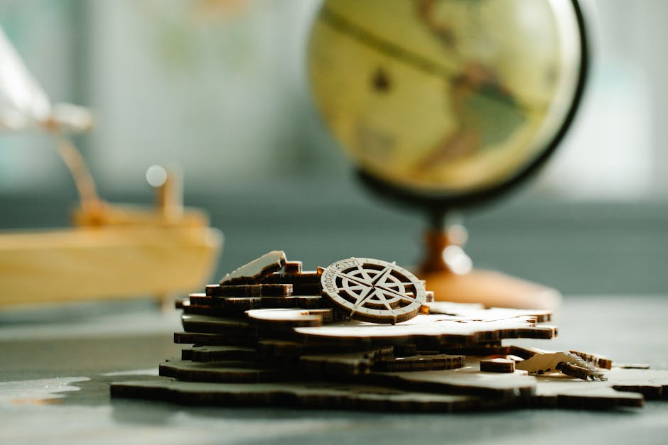 Artistic shot of wooden puzzle pieces with a globe in the background, symbolizing navigation and exploration.