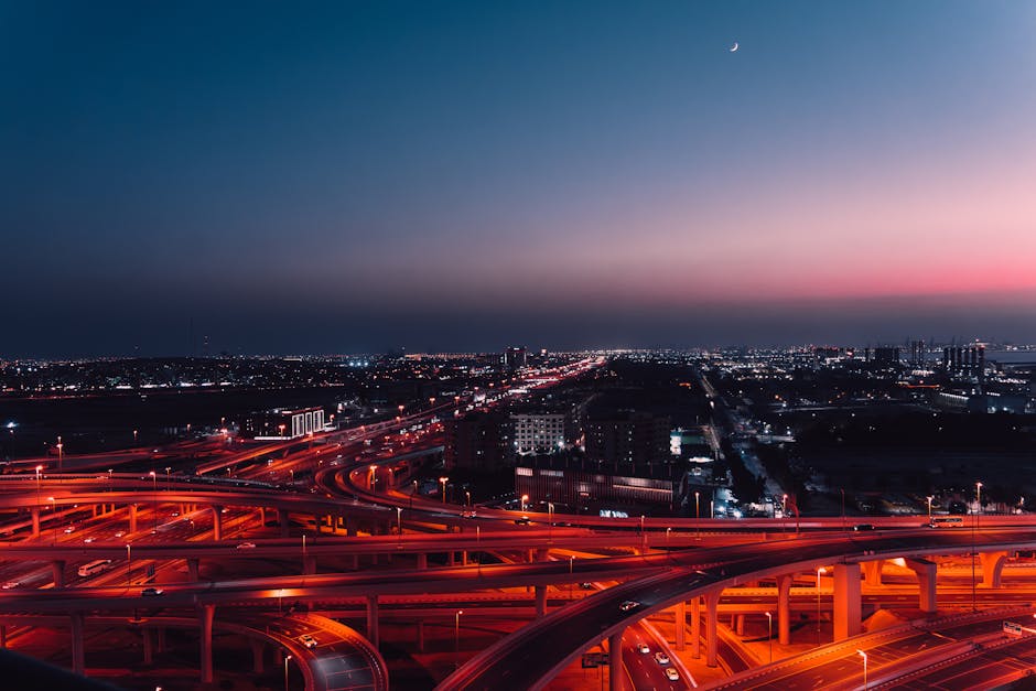 Stunning night view of Dubai's skyline with a brightly lit highway network under a crescent moon.