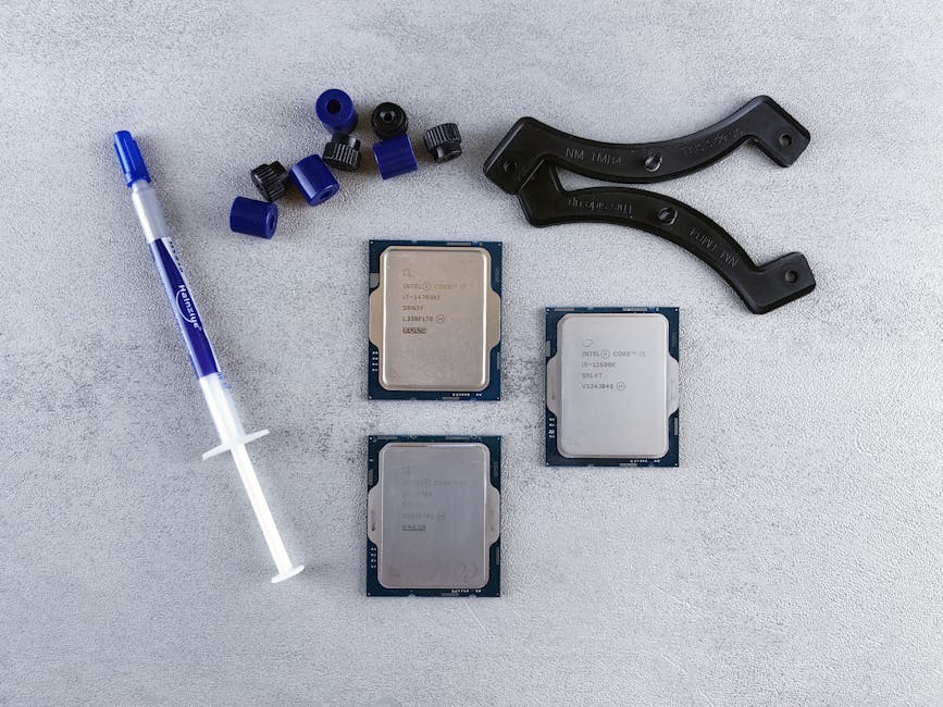 Top view of computer CPUs and thermal paste on a gray surface, showcasing modern technology components.